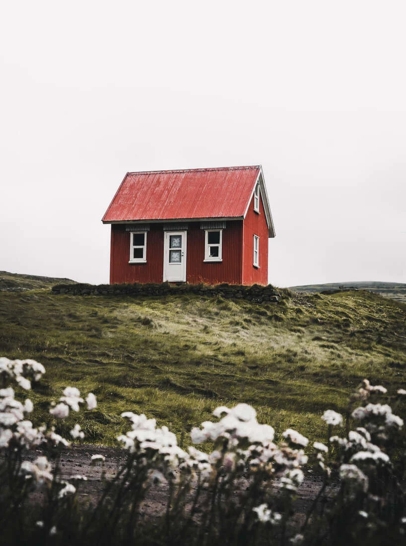 Small red cabin in a green meadow
