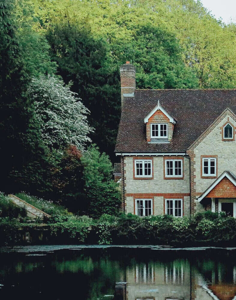 House reflected in a pond surrounded by trees