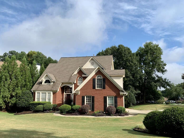 Brick house with a grey roof among trees